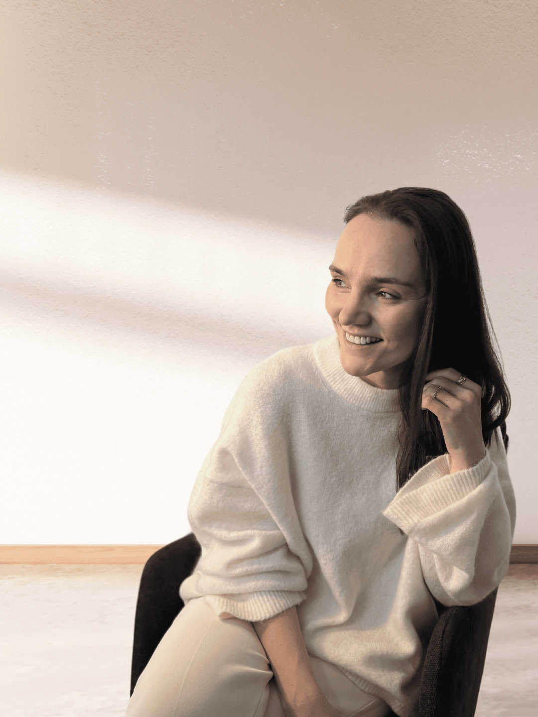 Olga is sitting on a char and smiling friendly to the side.